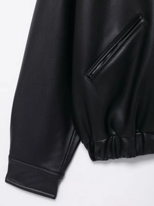 Detailed view of the faux leather jacket stitching, welt pockets and elastic hem finish