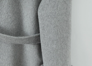 Detailed macro view of light gray wool blend fabric and stitched waist belt detail