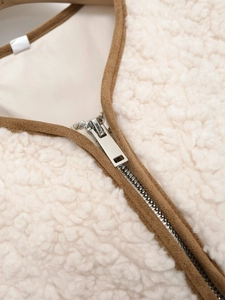 Detail of faux shearling vest featuring brown suede piping and silver metal zipper