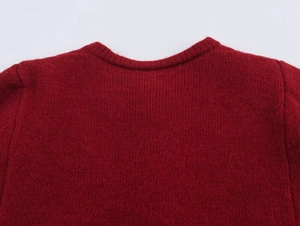 Detailed close-up of dark red knitwear featuring a ribbed round neckline and soft texture