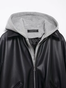 Detail of grey hood attachment and metal zipper on black faux leather jacket
