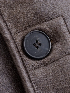 Gros plan détaillé sur la texture peau lainée marron foncé et le bouton noir mat à 4 trous