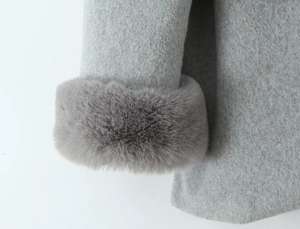Macro detail of soft faux fur trim on cuffs of a grey hooded wool coat for women