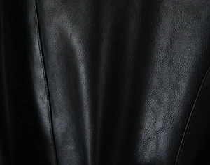 Close-up of premium black PU leather texture with natural lychee grain on the jacket