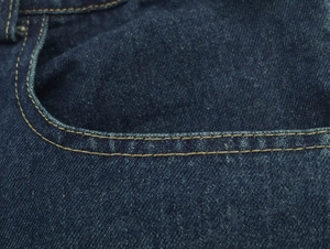 Detalle de pantalones vaqueros azul oscuro con doble costura dorada y textura denim