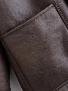 Détail de la veste en cuir marron foncé montrant les coutures et la texture naturelle
