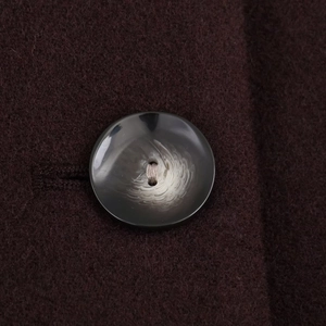 Macro shot of marble-textured round button on premium dark wool coat fabric