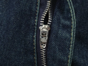 Primer plano de cremallera metálica y costuras de contraste en denim azul oscuro