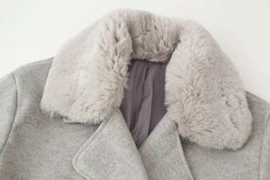 Détail du col en fausse fourrure douce et du tissu en laine sur un manteau gris
