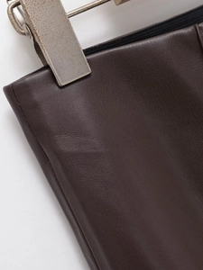 Gros plan sur la texture du cuir PU marron foncé et la taille élastique avec clip métal
