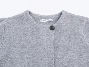 Detail of grey knit cardigan collar featuring a black button and fabric neck label