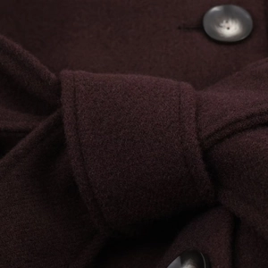 Macro view of dark burgundy wool coat belt knot and textured marble pattern button