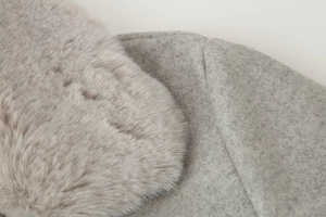 Détail du col en fausse fourrure et du tissu en laine texturé d'un manteau gris