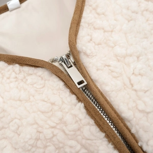 Faux shearling vest with round neck and adjustable waist in off-white with brown trim