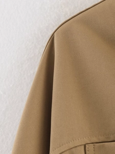 Close-up of khaki twill fabric texture and high-quality stitching on a women's jacket