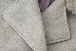 Détail du revers d'un manteau en laine gris clair avec col en fourrure synthétique