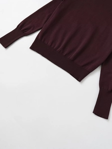 Detail of dark red knit sweater showing ribbed elastic hem and fine texture