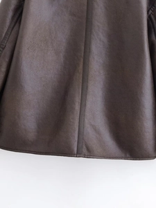 Détail de la texture en cuir synthétique marron avec passepoil vertical et coutures