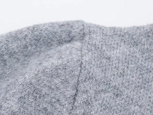 Close-up of grey mohair knit fabric showing textured brushed fibers and stitching details