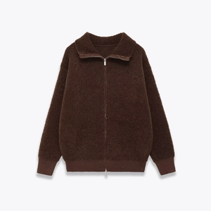 Detail view of dark brown sherpa jacket texture with metal zipper and ribbed cuffs