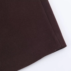 Close-up detail of dark chocolate wool fabric and stitching on long winter coat