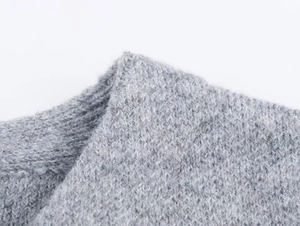 Close-up of light grey knit fabric texture with soft wool fibers and tight weave detail