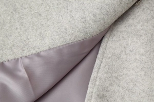 Détail du tissu en laine grise épaisse et de la doublure en satin lisse du manteau