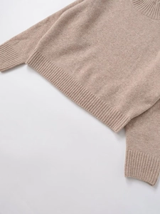 Detailed macro shot of ribbed knit texture on the neckline and cuffs of an oatmeal sweater