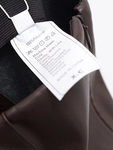 Vue détaillée de la taille élastique et de la fermeture éclair du pantalon en cuir PU brun