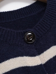Close-up of navy striped knit cardigan featuring ribbed collar and marble button detail