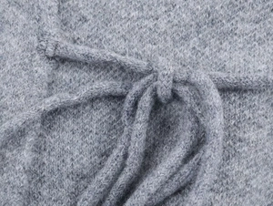 Detail shot of the gray knit texture and soft waist tie on a long-sleeve cardigan