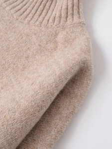 Detailed close-up of oatmeal knit sweater showing soft ribbed neckline and wool texture