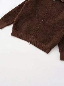 Close-up of dark brown knit jacket featuring textured bouclé fabric and silver zipper