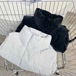 Detail of black and white cropped PU leather puffer vests in a metal shopping cart