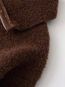 Detailed close-up of dark brown fuzzy faux shearling fabric with a metal zipper