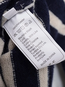 Macro shot of 100% polyester wash care label inside a navy striped knitted sweater