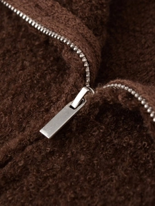 Detailed macro view of high-quality silver metal zipper on brown fleece jacket fabric