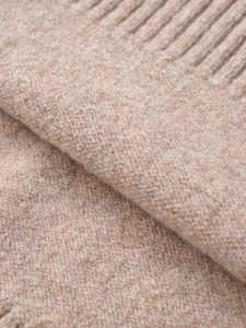 Macro view of high-quality beige knit fabric texture and ribbed hem detail