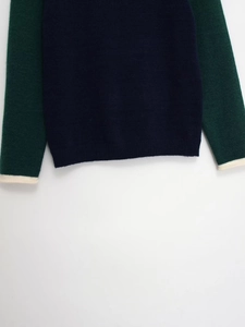 Détail d'un pull en maille color-block montrant l'ourlet bleu marine et les poignets
