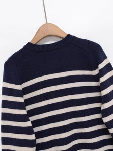 Detail view of the ribbed round neckline and blue-white striped knit texture of the sweater