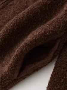 Detailed close-up of thick textured brown fleece fabric and side pocket on a winter jacket