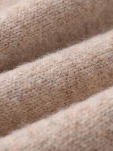 Macro shot of soft knit fabric texture and soft beige yarn fibers on women sweater