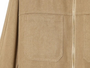 Detailed macro view of khaki cotton jacket with large patch pocket and metal zipper