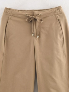 Close-up of khaki casual pants with elastic drawstring waist and gold metal aglets
