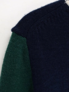 Gros plan sur la texture du tricot doux du pull bicolore à col rond pour femme
