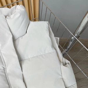 Detail of white quilted PU leather puffer vest with warm stand collar in a metal basket