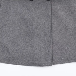 Detailed shot of grey wool coat bottom hem featuring two black buttons and straight stitching