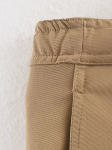 Close-up of khaki twill trousers showing elastic waistband and reinforced stitching details