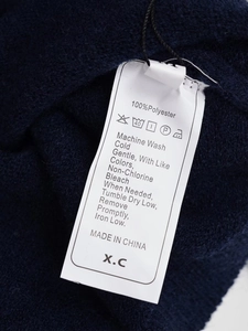 Gros plan de l'étiquette d'entretien montrant 100% polyester et instructions de lavage