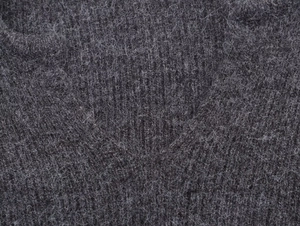 Close-up of charcoal gray ribbed knit fabric with soft wool texture and long fibers